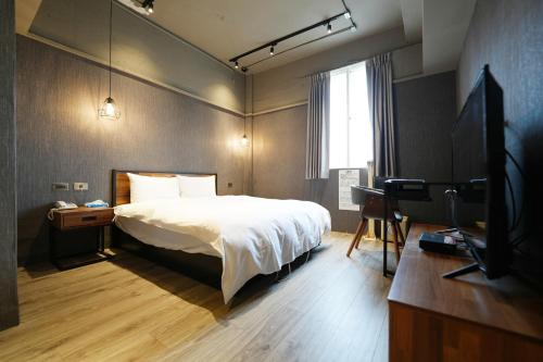 a bedroom with a bed and a flat screen tv at Puremeworld Hotel in Taipei