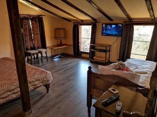 1 dormitorio con cama, mesa y TV en Къща за гости Старата череша село Раждавица en Rzhdavitsa