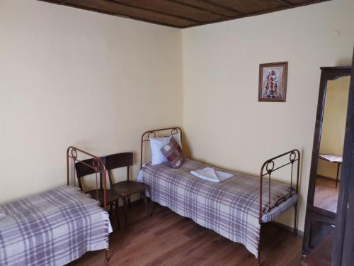 Habitación con 2 camas, silla y espejo. en Къща за гости Старата череша село Раждавица en Rzhdavitsa