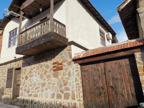 un edificio con puerta de madera y balcón. en Къща за гости Старата череша село Раждавица en Rzhdavitsa