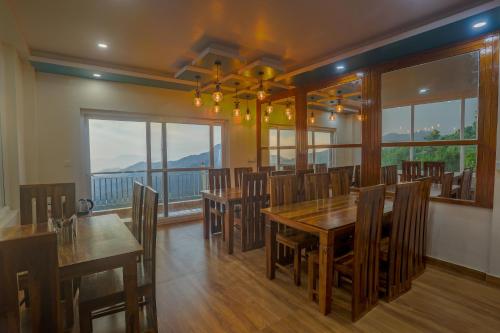 een eetkamer met een tafel en stoelen en een balkon bij Mukteshwar Treat Resort in Mukteswar