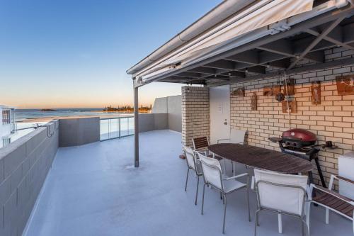 a patio with a table and chairs and a grill at Cotton Tree Waterfront with Jetty in Maroochydore