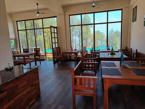 un restaurant avec des tables et des chaises en bois ainsi que des fenêtres dans l'établissement Lap Of Himalayas Resort, à Kausani