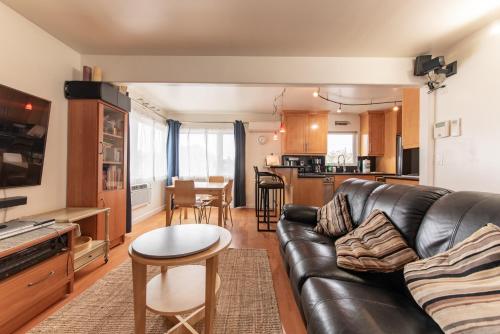 a living room with a leather couch and a kitchen at Newport Beach House 1 block from the beach FREE pickleball courts and 6 beach cruisers in Newport Beach