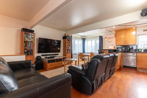 a living room with leather furniture and a kitchen at Newport Beach House 1 block from the beach FREE pickleball courts and 6 beach cruisers in Newport Beach