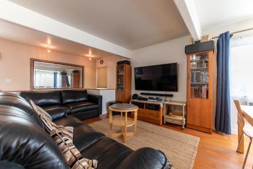 a living room with a leather couch and a flat screen tv at Newport Beach House 1 block from the beach FREE pickleball courts and 6 beach cruisers in Newport Beach