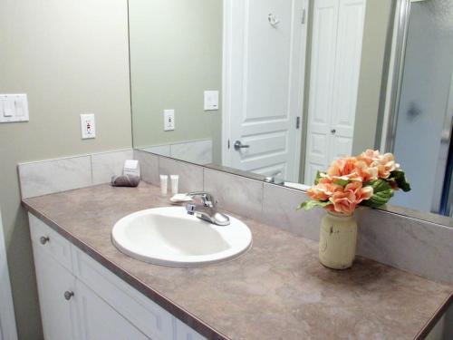 a bathroom with a sink and a vase with flowers at Paradise Canyon Golf Resort, Signature Condo 382 in Lethbridge
