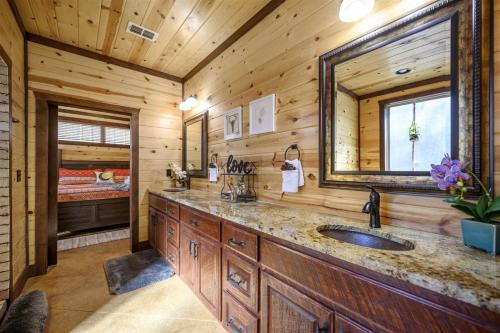 - une salle de bains en rondins avec lavabo et miroir dans l'établissement Indian Springs Lodge, à Broken Bow
