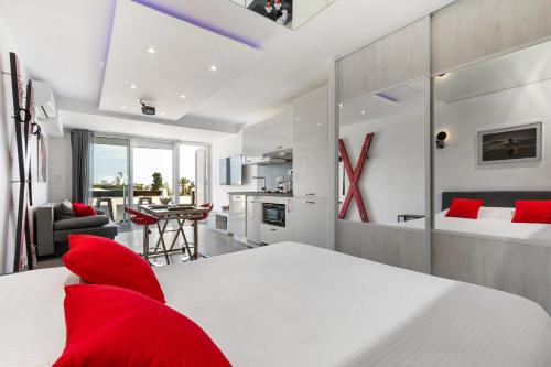- une chambre avec un lit blanc et des oreillers rouges dans l'établissement Village Naturiste R4N- Le Cerise Port Nature 5 Coursive, au Cap d'Agde