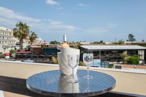 une table avec deux verres à vin sur un balcon dans l'établissement Village Naturiste R4N- Le Cerise Port Nature 5 Coursive, au Cap d'Agde