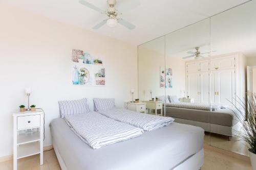 プエルト・デ・ラ・クルスにあるPrime Homes Taoro Atticの白いベッドルーム(ベッド1台、鏡付)