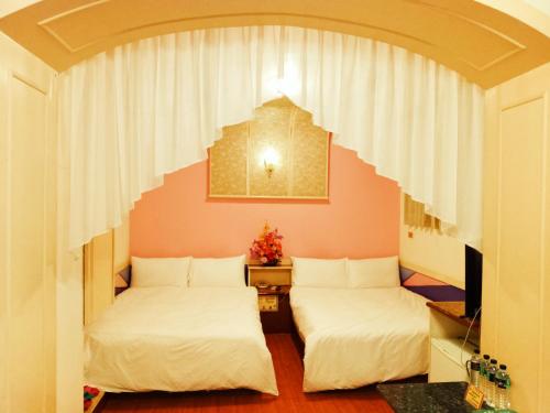 two beds are in a room with an arch at Shinge Hotel in Hualien City