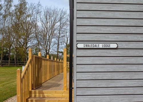 a sign on the side of a house with a wooden fence at Cleveland Hills View Holiday Park in Middleton upon Leven