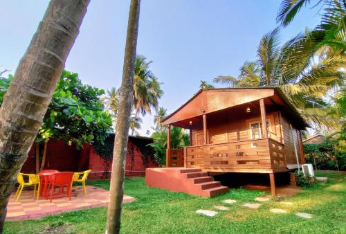 een klein houten huis met een tafel en stoelen bij Tranquil Beach Resort in Harihareshwar