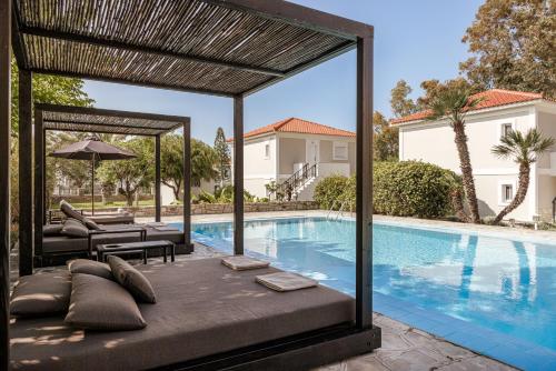 a swimming pool with a pergola next to a house at Doryssa Coast Apartments in Pythagoreio