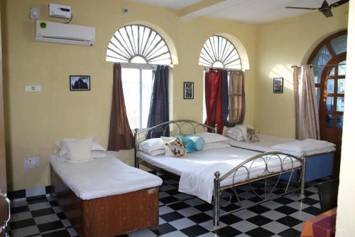 two beds in a room with two windows at "Priyadarshi Villa" Free pickup in ac car from Jasidih Railway station or Deoghar Airport in Deoghar