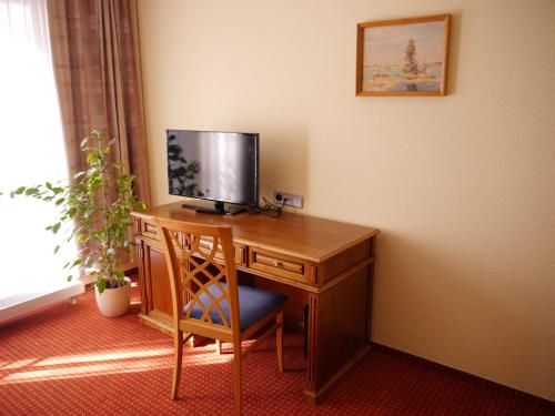 a desk with a television and a chair in a room at Garni-Hotel zum alten Ratskeller in Vetschau