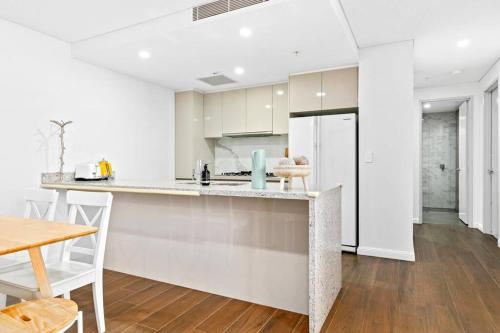 a white kitchen with a counter and a refrigerator at Four bedroom apartment with facilities in Olympic Park in Sydney