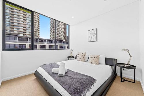 ein weißes Schlafzimmer mit einem Bett und großen Fenstern in der Unterkunft Four bedroom apartment with facilities in Olympic Park in Sydney