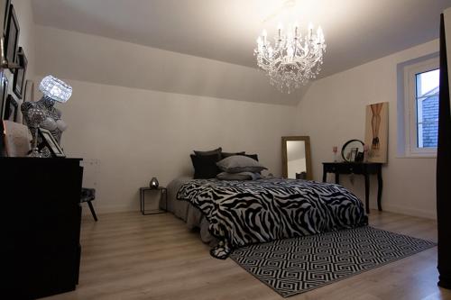 - une chambre avec un lit à motifs zébrés et un lustre dans l'établissement Nessmann, à Sarlat-la-Canéda