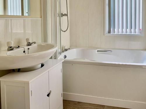 a white bathroom with a sink and a bath tub at Mallard Lodge in Gorleston-on-Sea