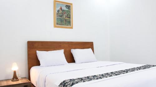 a bed with white sheets and a picture on the wall at Donna's Hus in Demangan