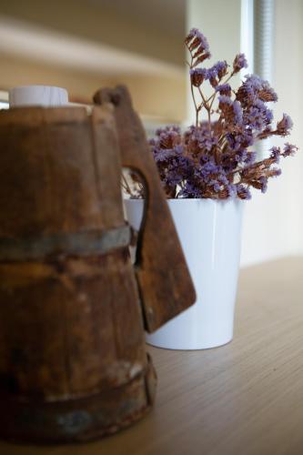 a white vase with purple flowers in it next to austedustedustedettel at Villa Pasithea in Korfos