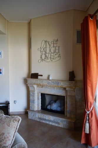 a living room with a stone fireplace with a sign on the wall at Villa Pasithea in Korfos