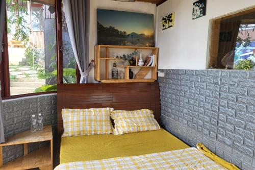a room with a bed and two pillows on a wall at Books Home Dalat in Da Lat