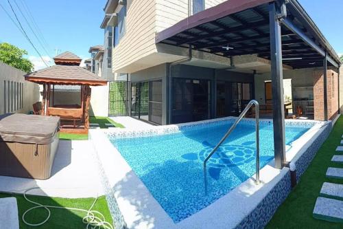 een zwembad met een prieel naast een huis bij 5BR w/ Covered Pool, Jacuzzi, & Gazebo 