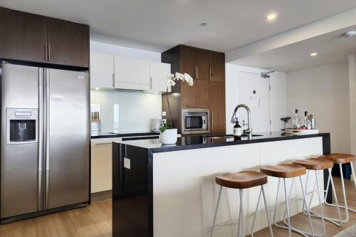 a kitchen with a stainless steel refrigerator and bar with stools at Modern luxury with breathtaking ocean views in Gold Coast