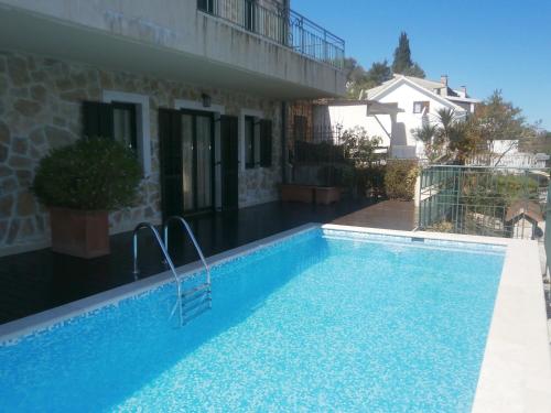 a swimming pool in front of a house at Apartment Tri Kiparisa in Tivat