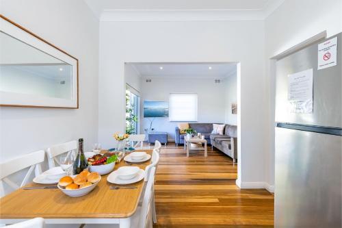 a dining room and living room with a table with fruit on it at Tomaree Cottage 12 Tomaree Road - 200 mtrs to Beach - Pet Friendly, linen, WiFi & aircon in Shoal Bay