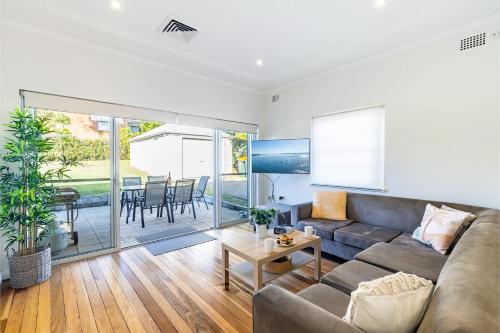 a living room with a couch and a table at Tomaree Cottage 12 Tomaree Road - 200 mtrs to Beach - Pet Friendly, linen, WiFi & aircon in Shoal Bay
