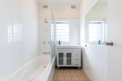 Un baño blanco con lavabo y ducha. en Tomaree Cottage 12 Tomaree Road - 200 mtrs to Beach - Pet Friendly, linen, WiFi & aircon, en Shoal Bay