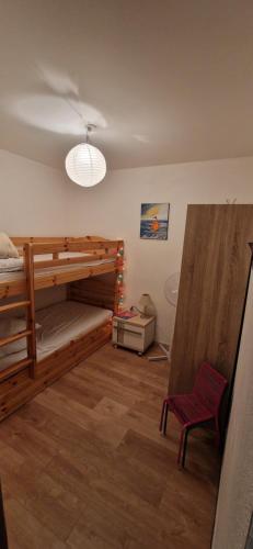 - une chambre avec des lits superposés et une chaise rouge dans l'établissement Charmant appart 40 m2 proche plage et marché Arago 141 rue de la printanière Le Musée, à Les Sables-dʼOlonne