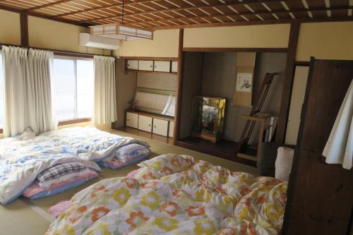 a bedroom with two beds and a window at Guesthouse ONE WORLD in Kitsuki