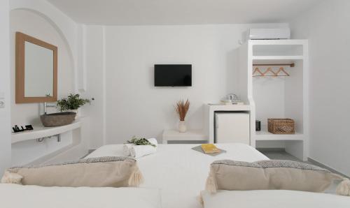 um quarto branco com 2 camas e uma televisão em Ippokampos Beachfront em Naxos Chora