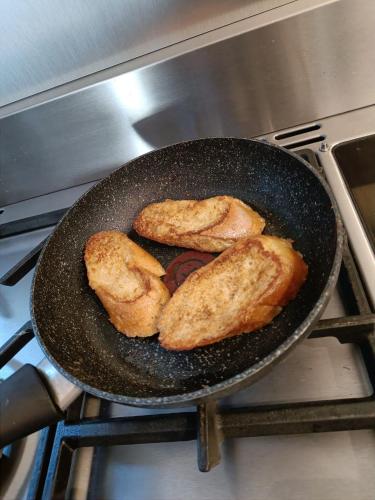 three pieces of bread frying in a pan on an oven at Maison d'hôtes "At'Home" in Ault