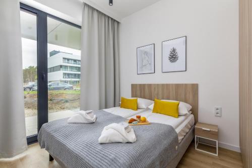 a bedroom with a bed with yellow and white pillows at Shellter Premium Apartment Beachside by Renters Prestige in Rogowo