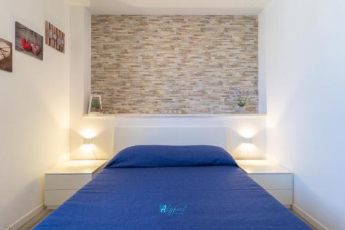 a bedroom with a blue bed and a brick wall at Mica apt in Alghero