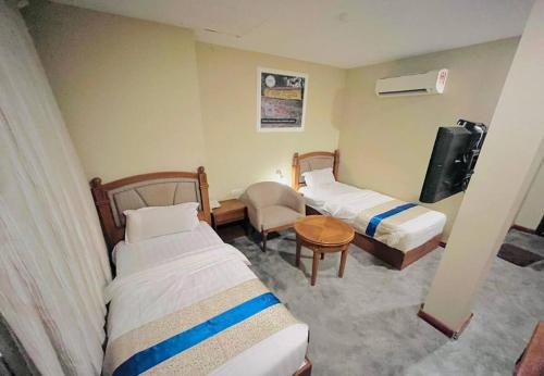 a hotel room with two beds and a table and a chair at Aladdin Dream Hotel in Johor Bahru