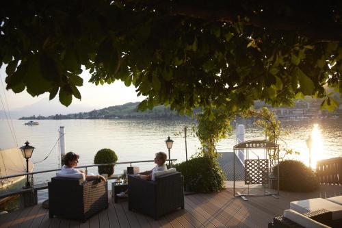 two people sitting in chairs on a patio by the water at Hotel Restaurant Seehof in Küssnacht