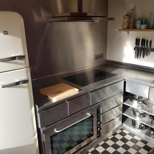 a kitchen with a stove and a refrigerator at Hotel Recour in Poperinge