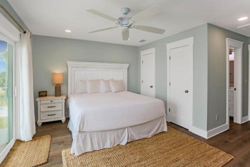 a bedroom with a white bed and a ceiling fan at Stay Salty in Saint Joe Beach