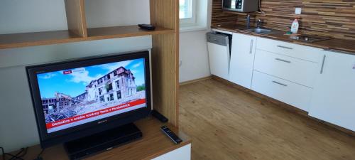 a flat screen tv sitting on a table in a kitchen at Aparthotel Rezidence Club Canada Lipno in Lipno nad Vltavou