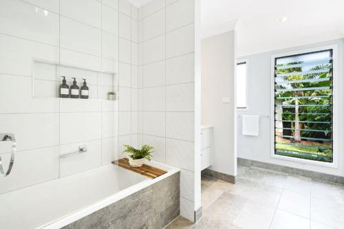 FreshwaterにあるMaison Daintree - Mount Whitfield Viewの浴槽と窓のある白いバスルーム