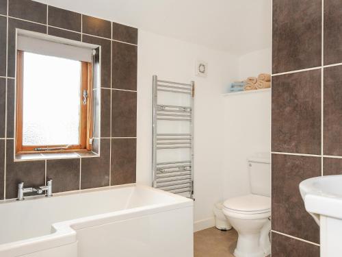 a bathroom with a tub and a toilet and a sink at Great Brightor Cob Barn in Bodmin