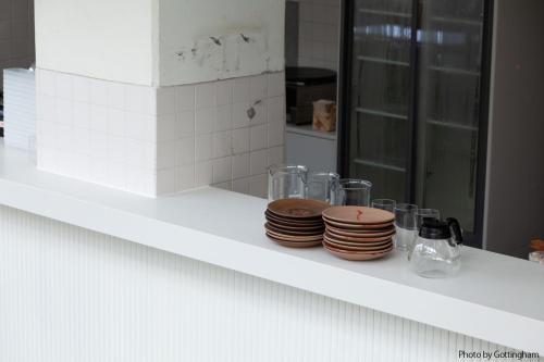 a white counter with plates and glasses on it at KIRO Hiroshima by THE SHARE HOTELS in Hiroshima