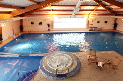 a large swimming pool with a tub in a building at Best Western Kings Manor in Edinburgh